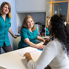 Patient sitting at desk with dental team members