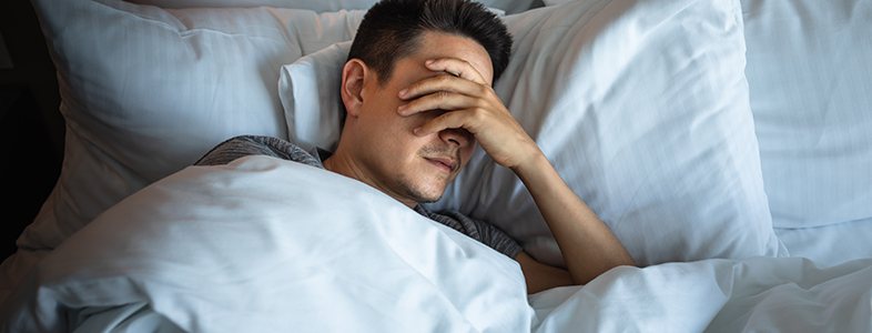 Man in bed, struggling to sleep