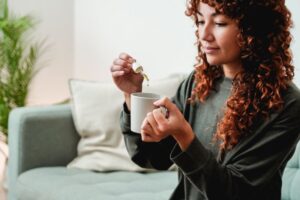 Woman placing CBD oil in her cup of tea
